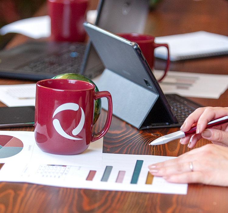 Closeup shot of red mug with SeQuel Response logo and sheet of data