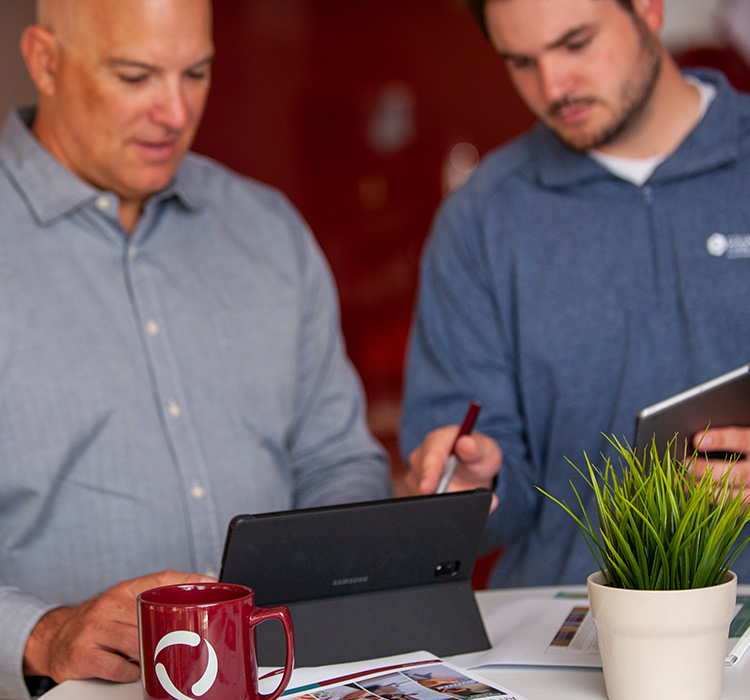 Workers using laptop and tablet to compare work