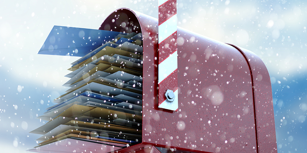 Red mailbox filled with holiday mailings on a snowy cold background.