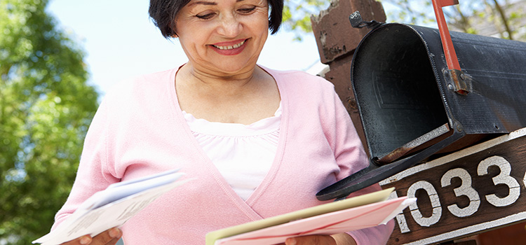 Woman checks mail box and smiles